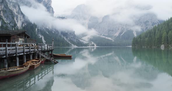 Small Boathouse with Wood Pier and Boats on Braies Lake with Cloudy Weather