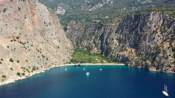 aerial drone panning right across Butterfly Valley and the blue ocean with boats anchored in the bay