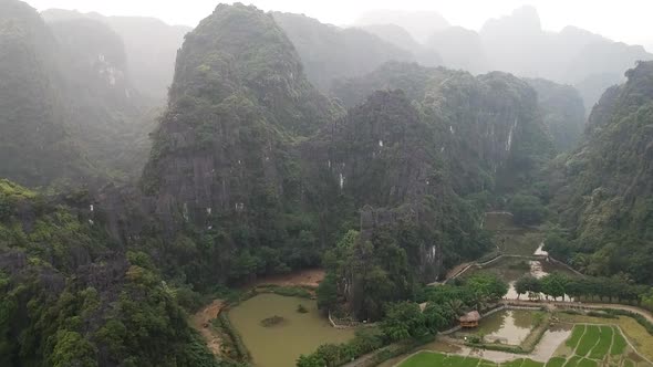 Aerial hazy view of rocky Vietnamese countryside. Fly over giant limestone rocks in Tam Coc, Ninh Bi