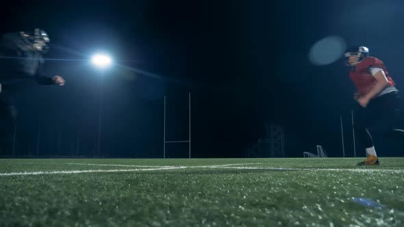 Two American Football Players Running on a Field, Playing American Football, Side View.