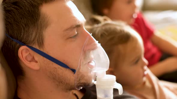 Father in Inhaler Mask Rests on Sofa with Kids at Home