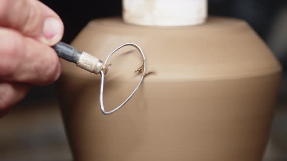 Potter's Hand Removes Irregularities From Clay Jug with Special Scraper