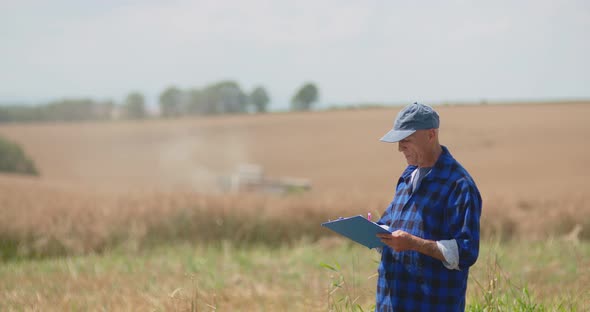 Mature Male Farmer Writing On Clipboard At Farm