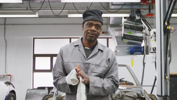 African American male car mechanic cleaning his hands with a rag