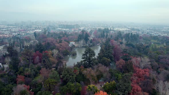 Aerial dolly in of artificial pond surrounded by colorful autumnal trees and vegetation in O'Higgins