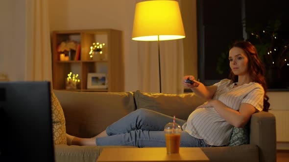 Pregnant Woman with Remote Control Watching Tv