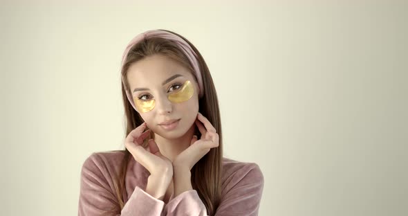 Woman Applying Hydrogel Undereye Recovery Patches on a Light Background