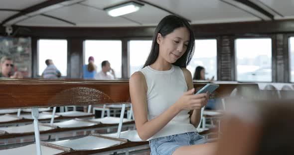 Woman use of smart phone in ferry of Hong Kong city 