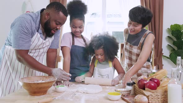 Happy African American kids and family preparing flour to make bread in kitchen at home.