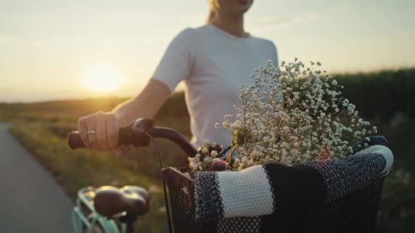 Cheerful caucasian woman of middle age walking with a bike on sunset on village road. Shot with RED