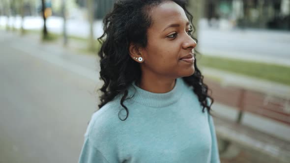 Pretty brunette African woman wearing blue sweater walking