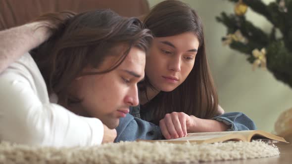 Young Attractive Couple in Love Lying on the Carpet in the Bedroom Covered with a Blanket