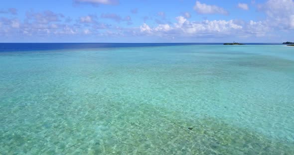 Beautiful fly over travel shot of a sandy white paradise beach and aqua blue water background in hig