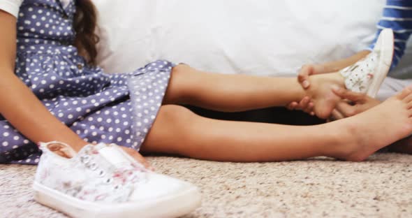 Mother helping her daughter to wear a shoes in bedroom 4k