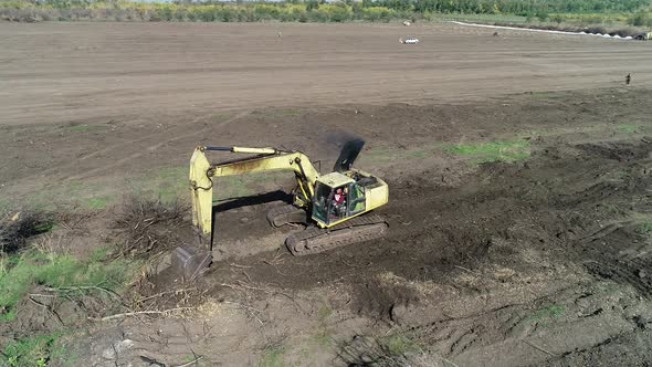 Excavator is Moving Around Some Tree Branches in the Field Heavy Machinery