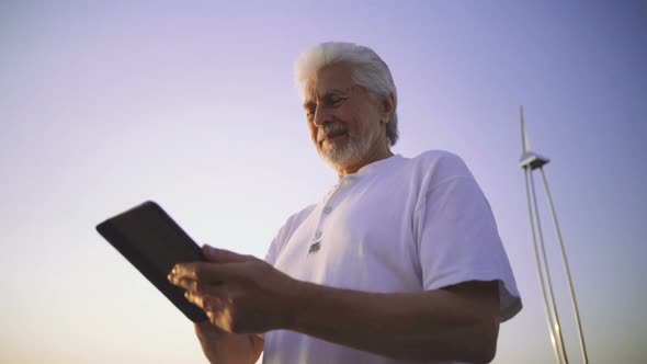 Portrait of Retirement Handsome Senior Man Using Tablet Computer on Seafront and Smiling