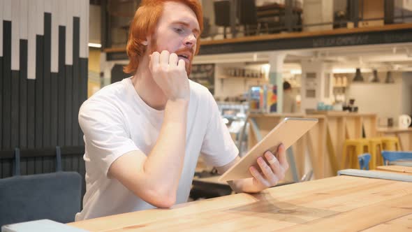 Casual Redhead Beard Man Using Tablet PC in Cafe