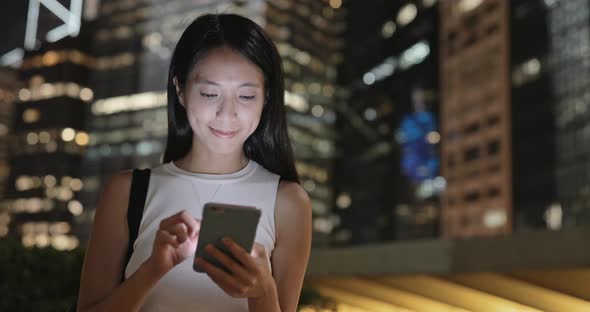 Woman using mobile phone at night in Hong Kong 