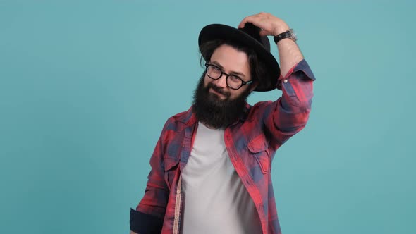 Bearded Man in Casual Outfit and Glasses. He Smiling, and Taking a Hat Off.