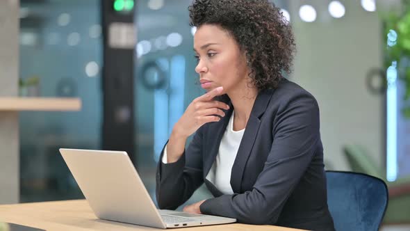 Pensive African Businesswoman Thinking While Working on Laptop