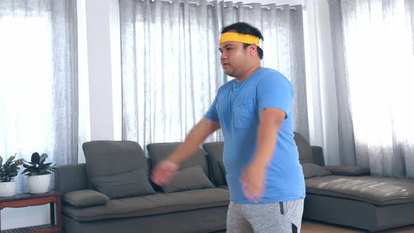 Overweight Man Doing Squat Exercises At Home In His Living Room