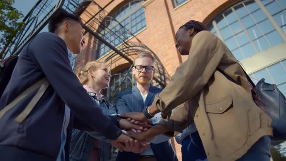 Low Angle View of Diverse Millennials Friends Stacking Hands Together Outdoors