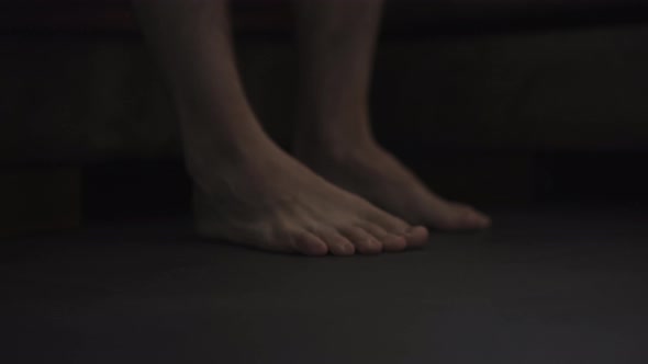 Dark Morning Shot of Man Feet on the Floor Near Bed