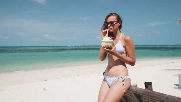 Woman Drinking From Coconut Wearing Sunglasses on Beach