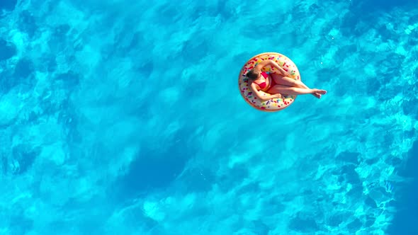 Aerial View of a Woman in Red Swimsuit Lying on a Donut in the Pool