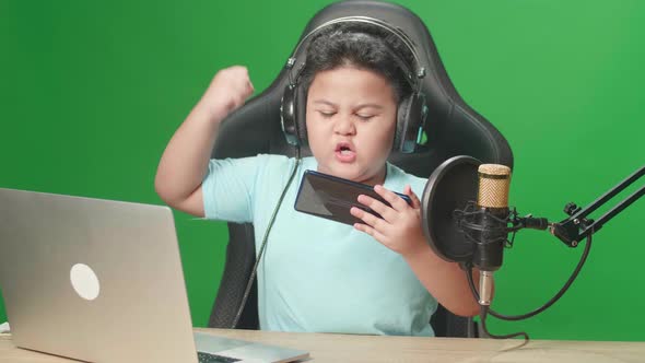 Little Boy Playing Video Game With Mobile Phone Then Celebrating While Live Stream On Green Screen