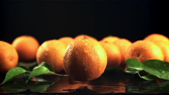 A Juicy Tangerine Falls on the Table with Splashes of Water