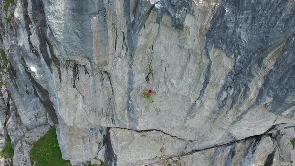 Aerial drone view of a man rock climbing up a mountain.