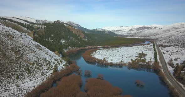 The cameraes slowly over a mirrored river surrounded by rocky mountains with the sun going down.