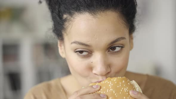 Portrait of African American Woman with an Appetite for Biting a Hamburger