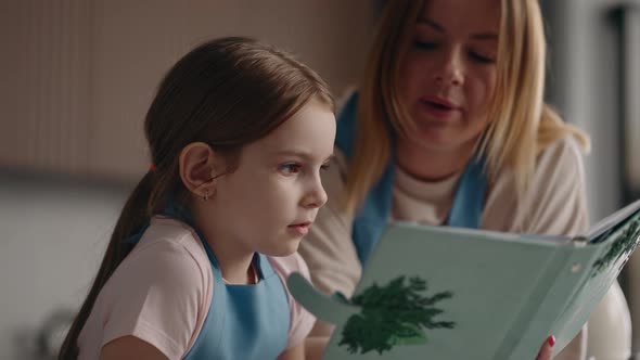 Careful Mother is Teaching Her Preschooler Daughter to Cook Reading Receipt in Cookery Book