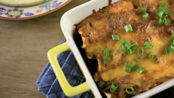 Chicken enchiladas with cheddar cheese and sauce.