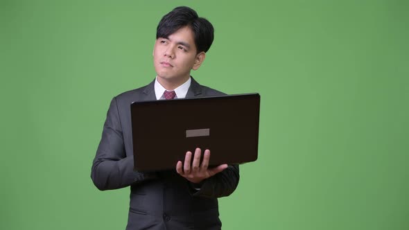 Young Handsome Asian Businessman Using Laptop