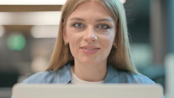 Close Up of Woman Smiling at Camera While Using Laptop