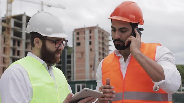 Engineer Speaks on Mobile Phone on Construction Site and Checks the Work of the Worker. Builder
