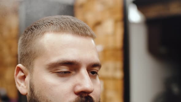 Styling the Hair of a Caucasian Man a Hairdresser Sprays Hairspray Closeup