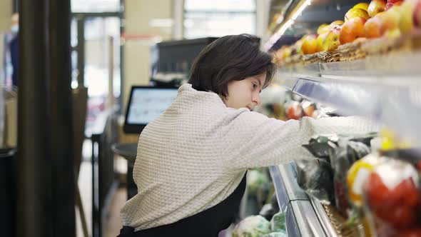 Woman with Down Syndrome Restocking Fresh Fruits in a Grocery Store