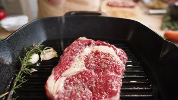 Male Chef Salting Meat Steak on Grill Pan