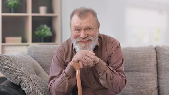 Portrait Happy 80s Grandfather Smiling Posing with Walking Stick Sitting on Couch at Home