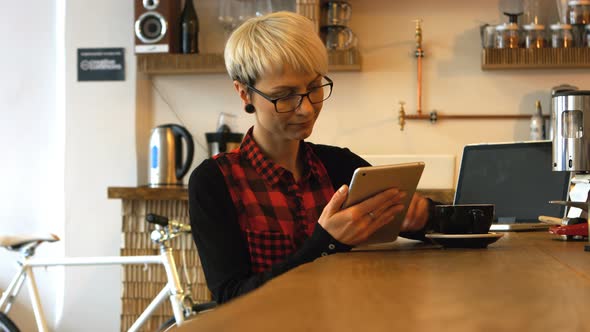 Female business executive using digital tablet while having coffee