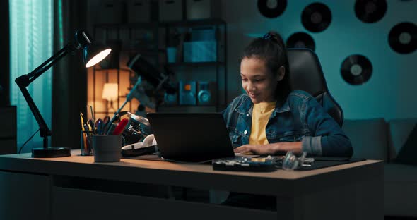 Focused Smiling Teen Uses Laptop at Home Looking at Screen Chatting Reading or Writing Email Paper