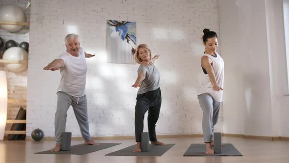 Caucasian Husband and Wife Doing Yoga with Teacher in Studio
