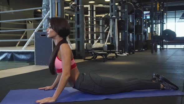 A Young Girl Does a Special Exercise for the Back Lying on the Mat