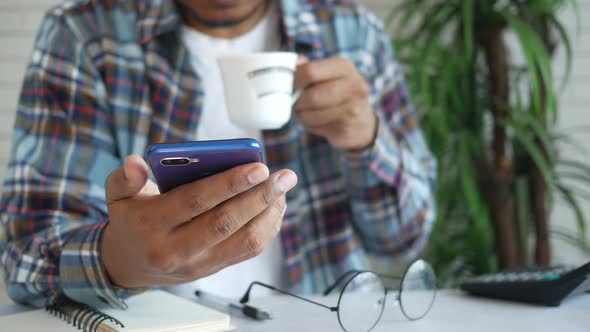 Young Man Using Smart Phone and Drinking Tea White Sited