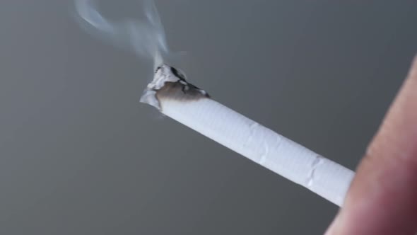 Close Up Holding a Burning Cigarette on Black Background