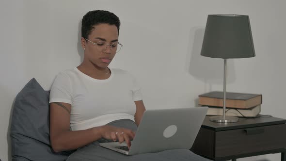 African Woman Showing Thumbs Down Sign While Using Laptop in Bed